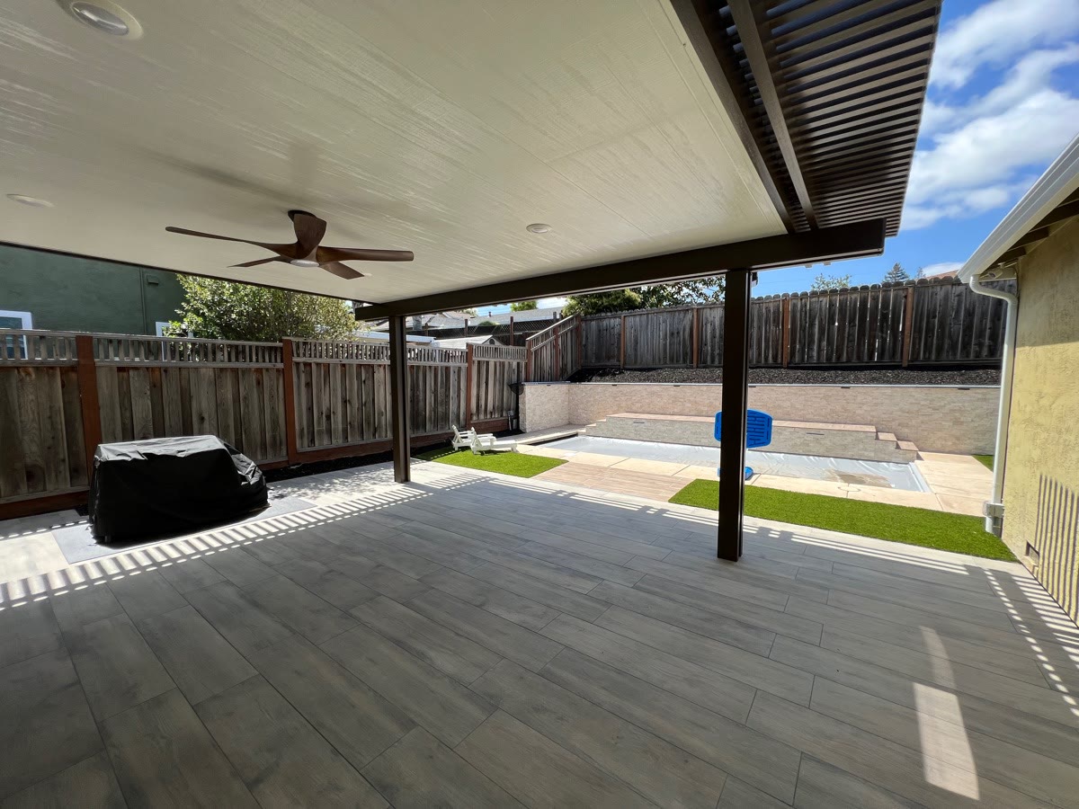 Covered patio with ceiling fan and lattice shade extension by FG Pavers and Turf.