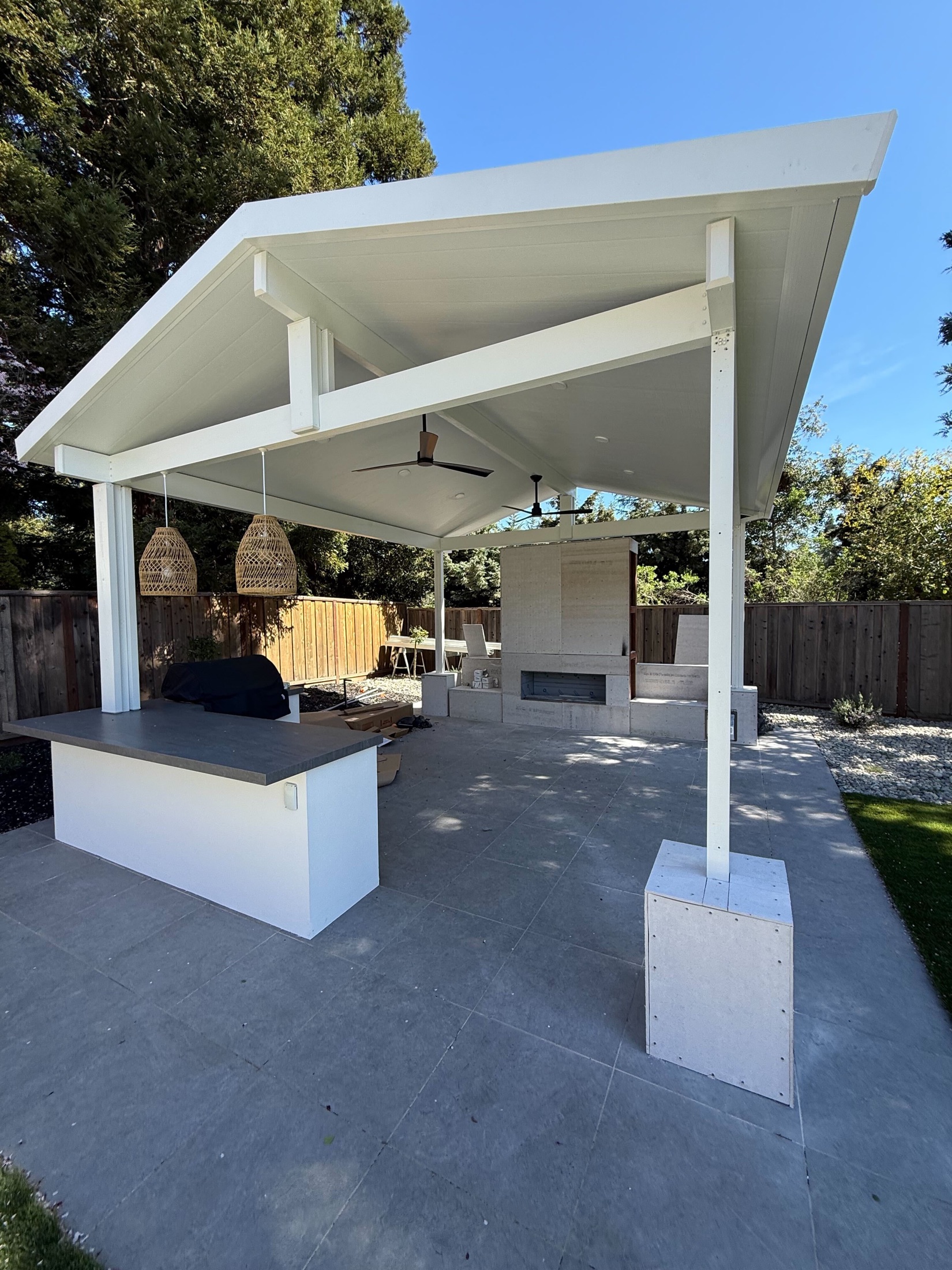 Finished Danville covered patio with outdoor fireplace, kitchen, stone columns, and turf by FG Pavers and Turf.