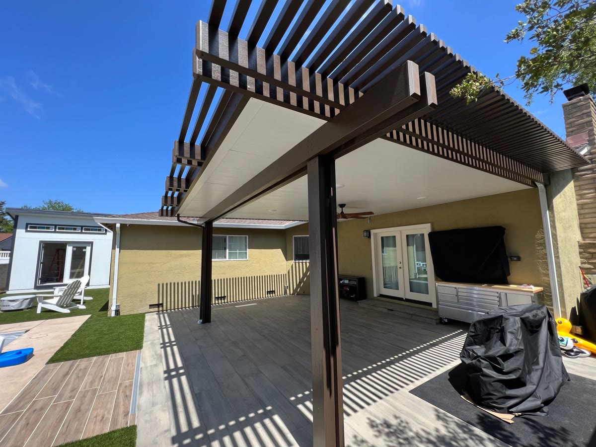 Dark lattice patio cover attached to a backyard patio by FG Pavers and Turf.
