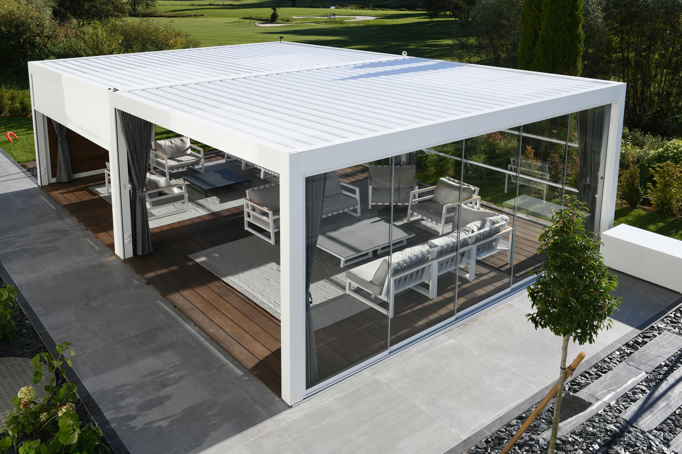 Pergo Centro SO Climate coupled louvered pergola with sliding glass walls and outdoor lounge seating.