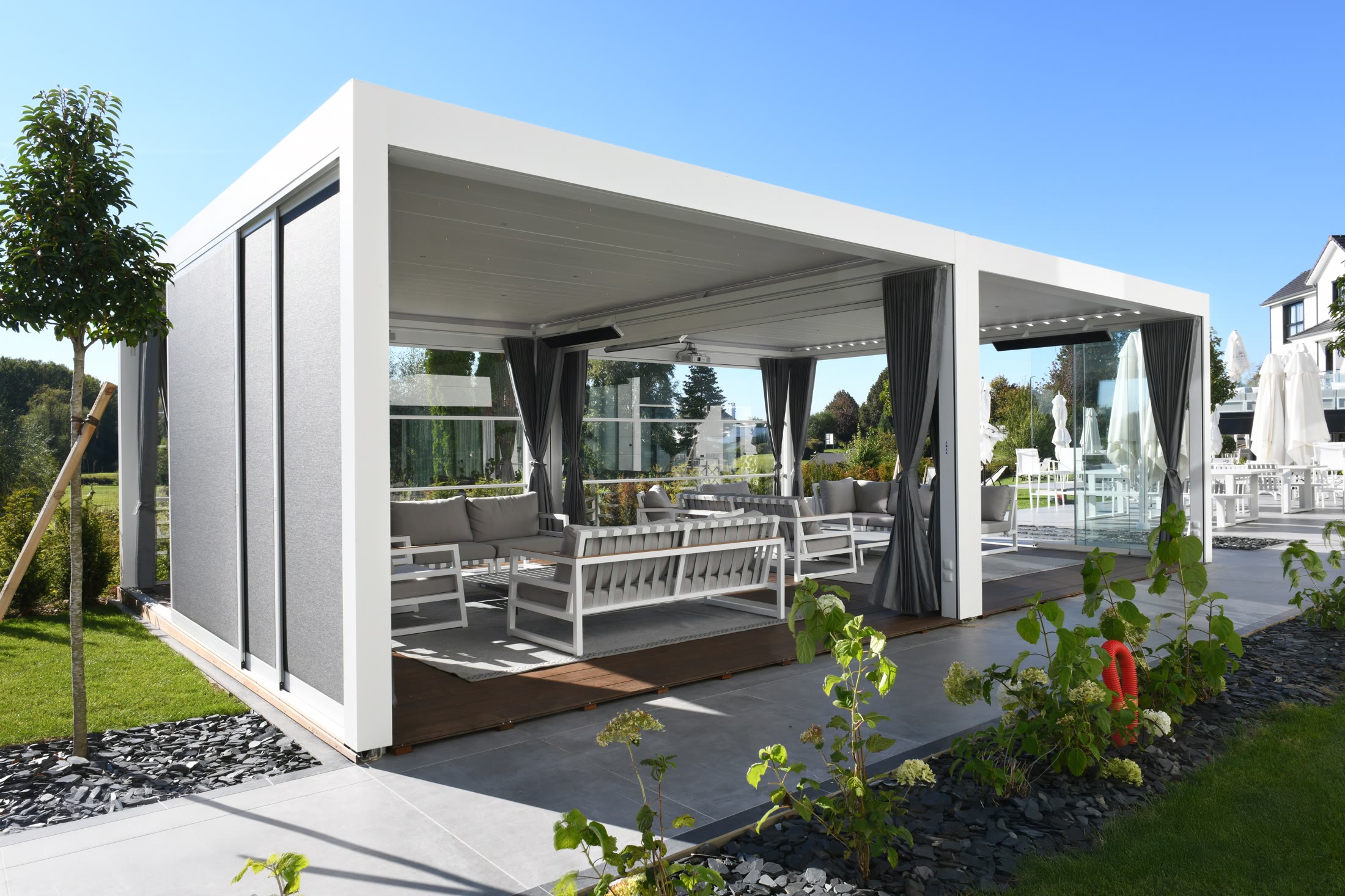 Pergo Centro SO Climate double pergola with curtains, glass panels, shade screens, and lounge seating.