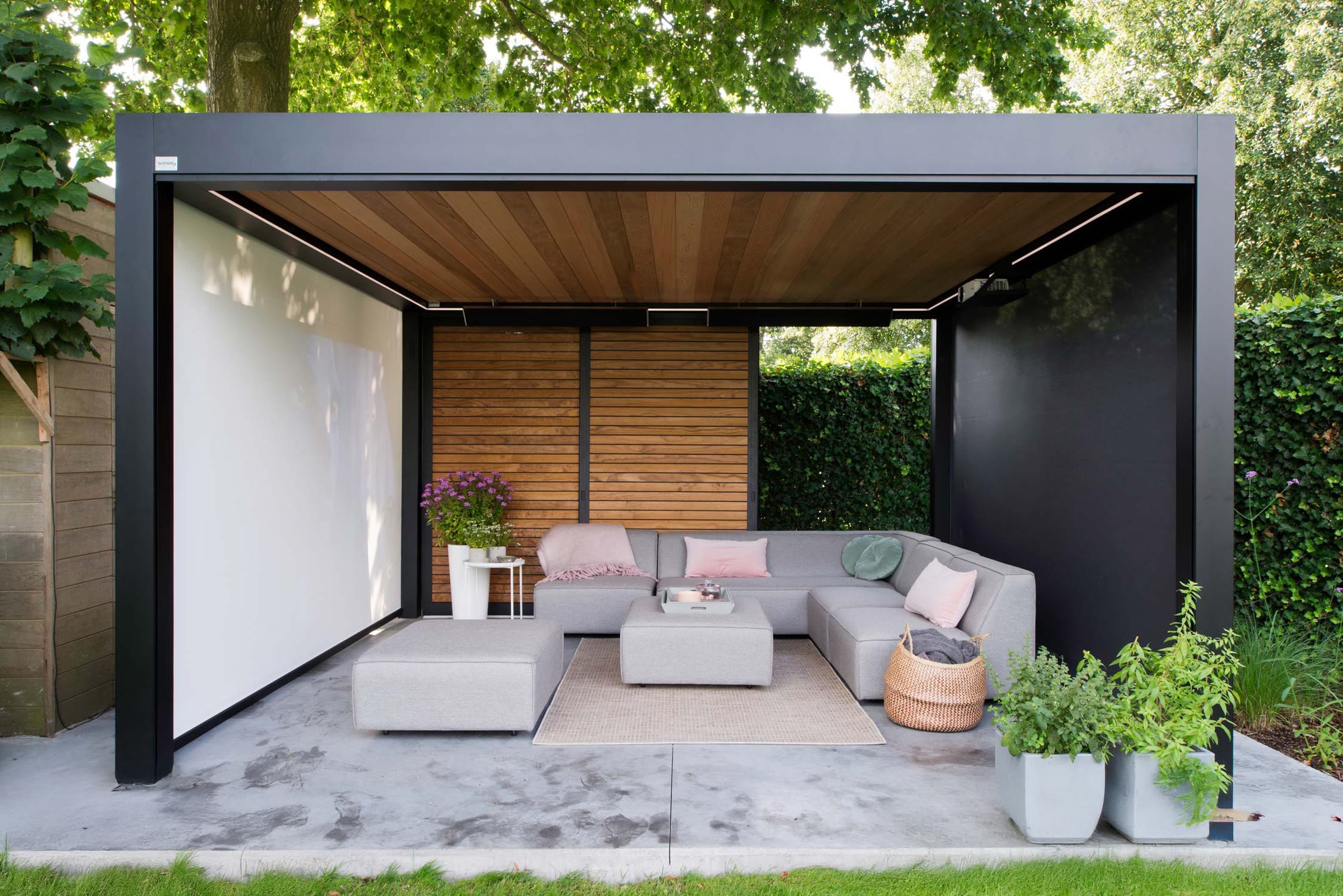 Pergo Centro SO Climate louvered pergola with wood-look walls, screens, and an outdoor lounge.
