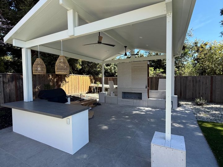Finished Danville covered patio with outdoor fireplace kitchen stone columns and turf.