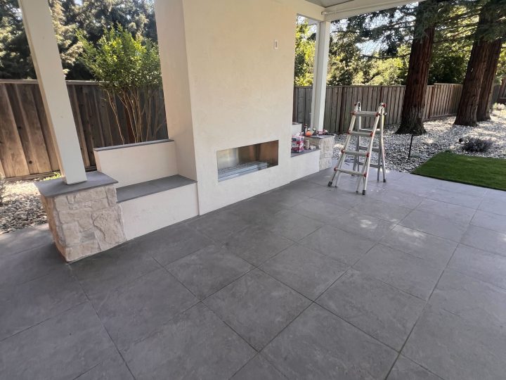 Finished fireplace and porcelain tile beneath the covered patio beside the Danville turf area.