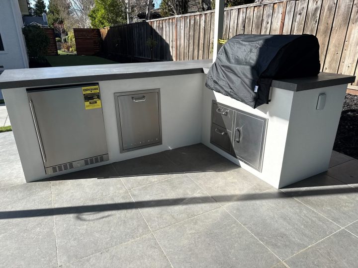 Finished outdoor kitchen with built-in barbecue and counters beneath the Danville patio cover by FG Pavers and Turf.