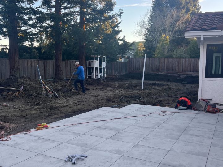 Large-format patio pavers during installation beside the Danville detached patio cover area.