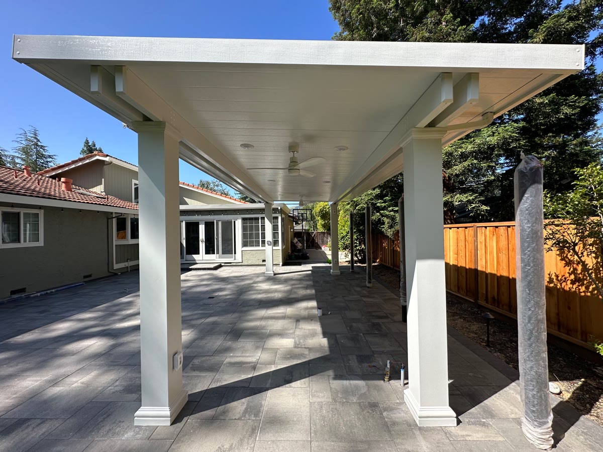 White solid patio cover with square columns over a paver patio by FG Pavers and Turf.