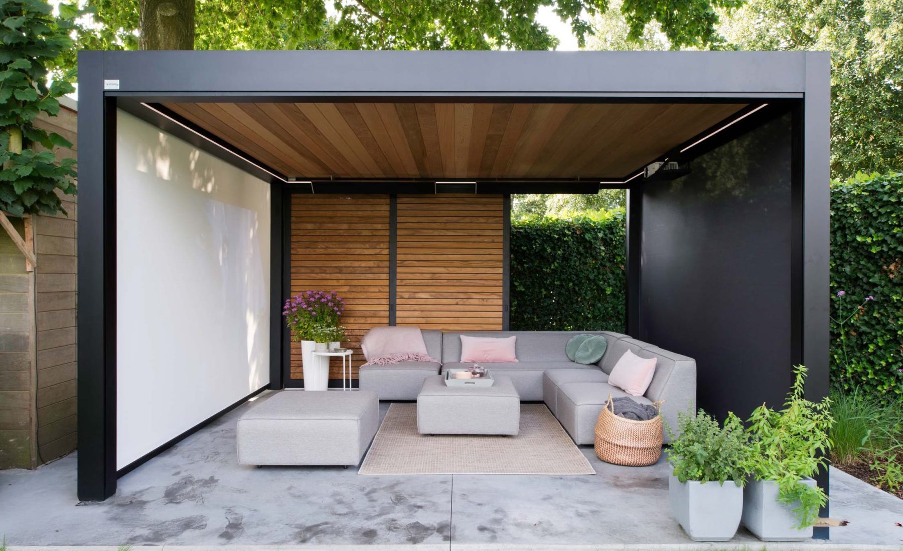 Pergo Centro SO Climate louvered pergola with wood-look walls screens and an outdoor lounge.