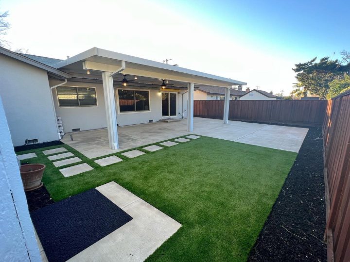 Finished Livermore backyard with a white modern patio cover, concrete patio, turf, and stepper walkway by FG Pavers and Turf.