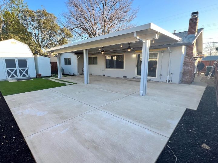 Wide view of a Livermore covered concrete patio with white patio cover and turf by FG Pavers and Turf.