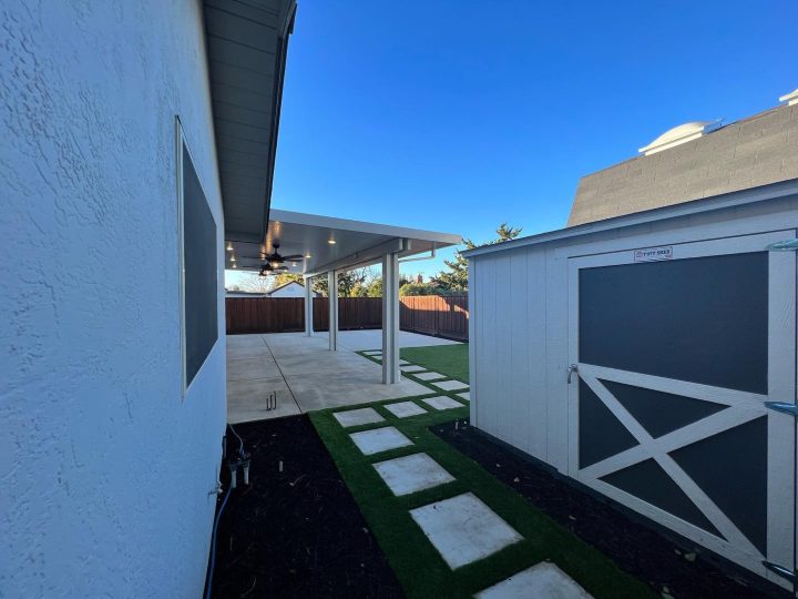 Turf stepper walkway leading toward a covered concrete patio in Livermore by FG Pavers and Turf.
