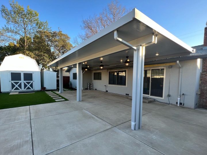 White solid patio cover over a large concrete patio with turf in Livermore by FG Pavers and Turf.