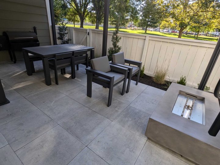 Covered dining and seating patio under a black louvered patio cover in Pleasanton by FG Pavers and Turf.