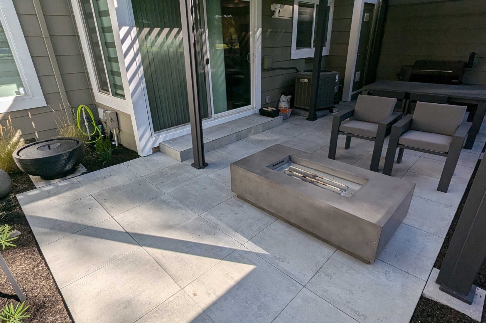 Black louvered patio cover over a Pleasanton paver patio with outdoor seating and a fire table by FG Pavers and Turf.