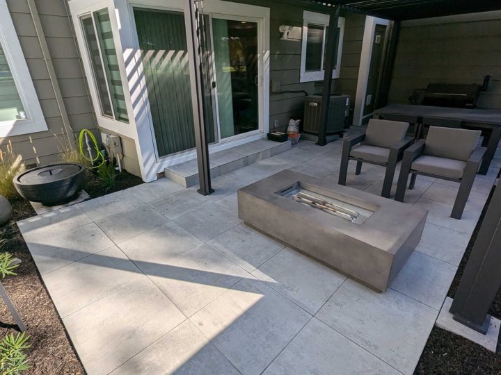 Black louvered patio cover over a Pleasanton paver patio with outdoor seating and a fire table by FG Pavers and Turf.