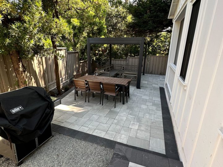 Freestanding pergola with lounge seating beyond a dining area on a Menlo Park paver patio